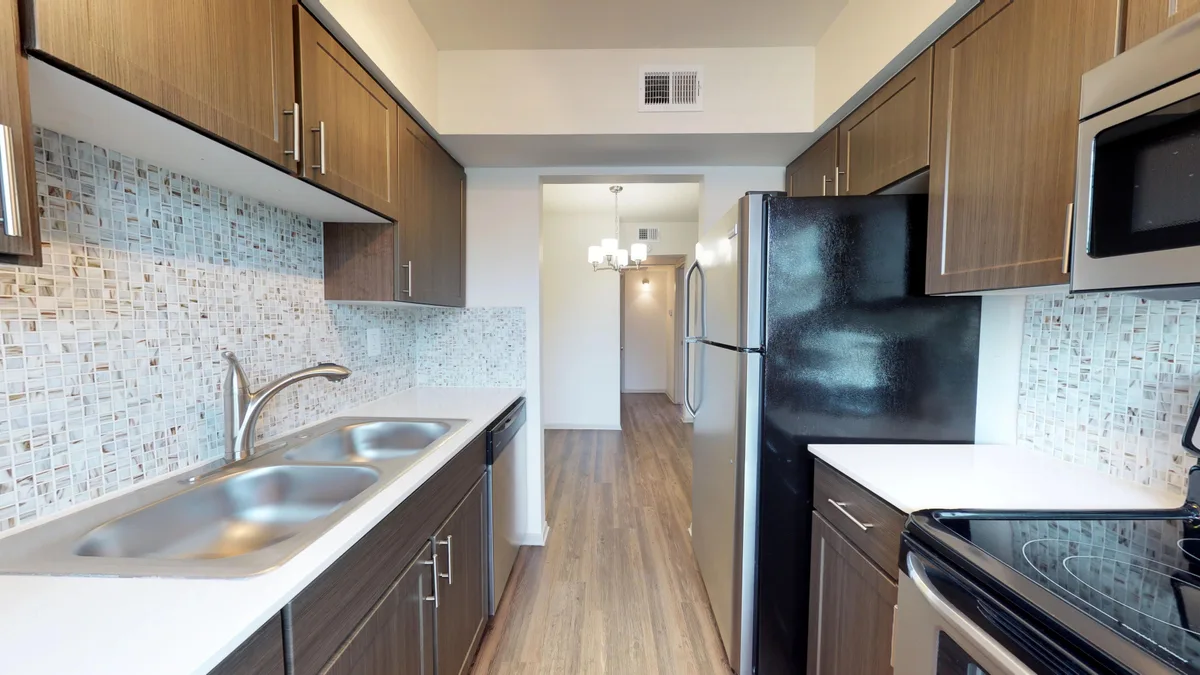 Galley kitchen with espresso cabinets, stainless range and microwave, and mosaic tile backsplash