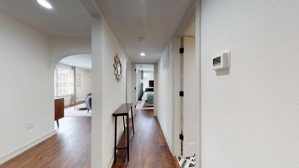 Interior apartment hallway with hardwood floors, slim console table and a sunburst mirror