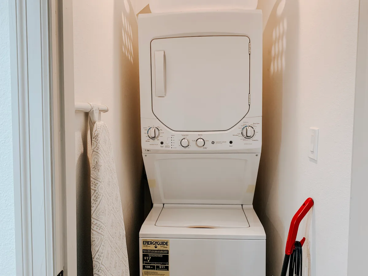 In-unit stacked white washer and dryer in a laundry closet
