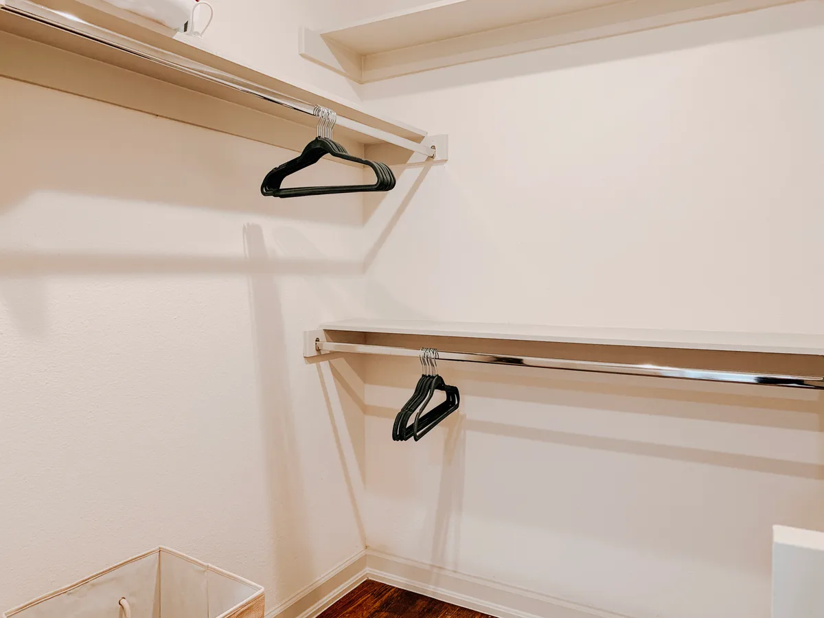Walk-in closet with double-tier hanging rods, shelving and a fabric laundry hamper