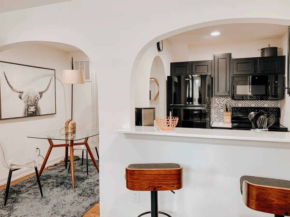 Breakfast bar with wood swivel stools overlooking the black kitchen and the studio bed beyond