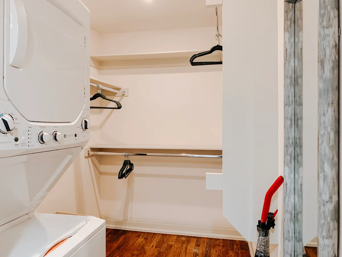 Walk-in closet with shelving, hanging rods and a stacked white washer and dryer