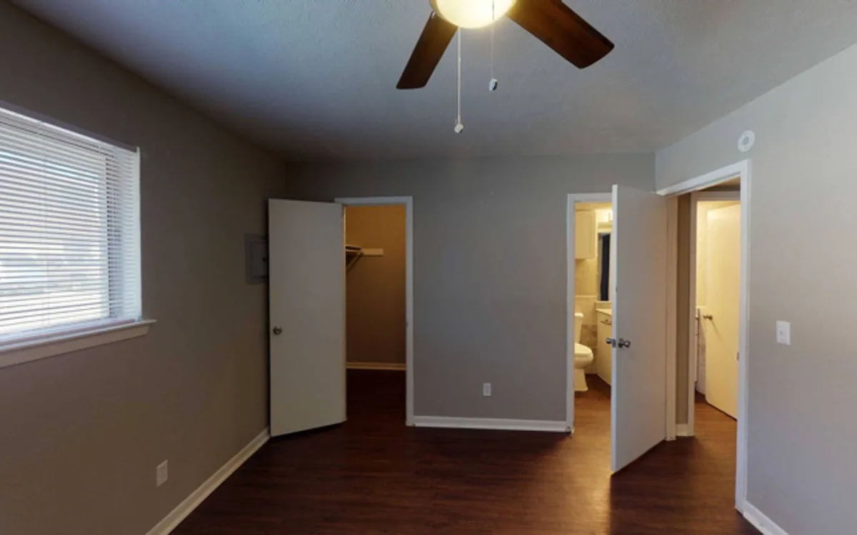 Bedroom with ceiling fan opening to a walk-in closet and an ensuite bathroom