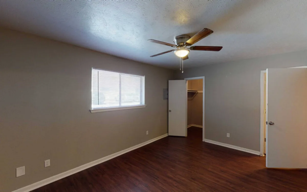 Bedroom with wood-style floors, ceiling fan, window blinds, and a walk-in closet