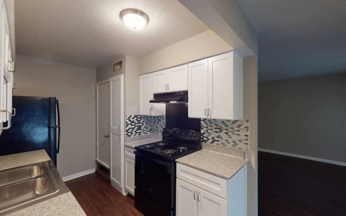 Kitchen with white shaker cabinets, black appliances, and speckled granite-look countertops