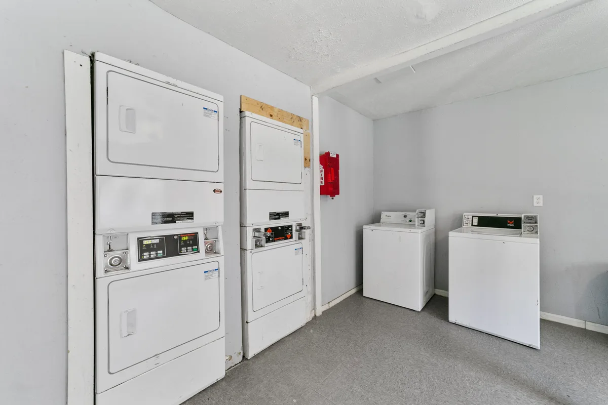On-site laundry facility with stacked dryers and top-loading washing machines