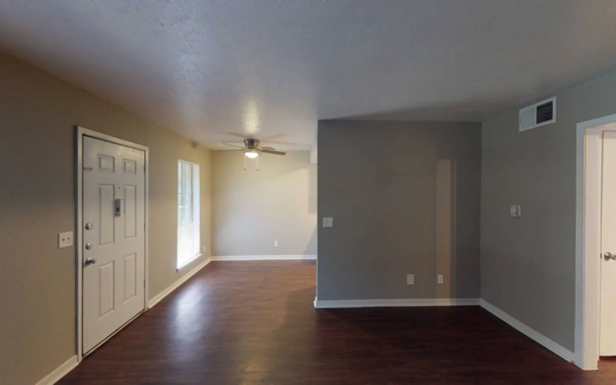 Open living room with dark wood-style flooring, ceiling fan, and two-tone painted walls