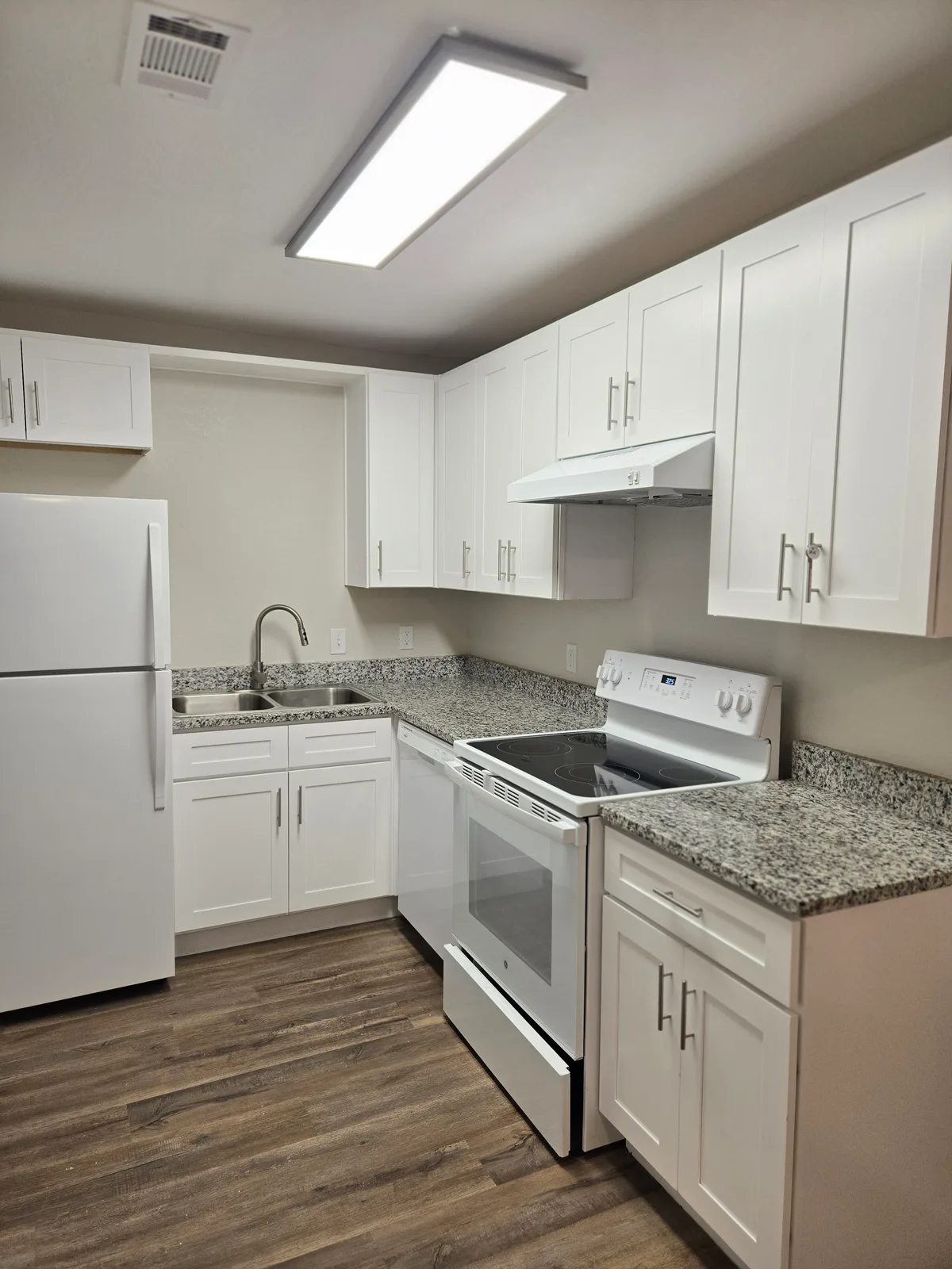 L-shaped kitchen with white shaker cabinets, granite countertops, a white electric range, and wood-look flooring