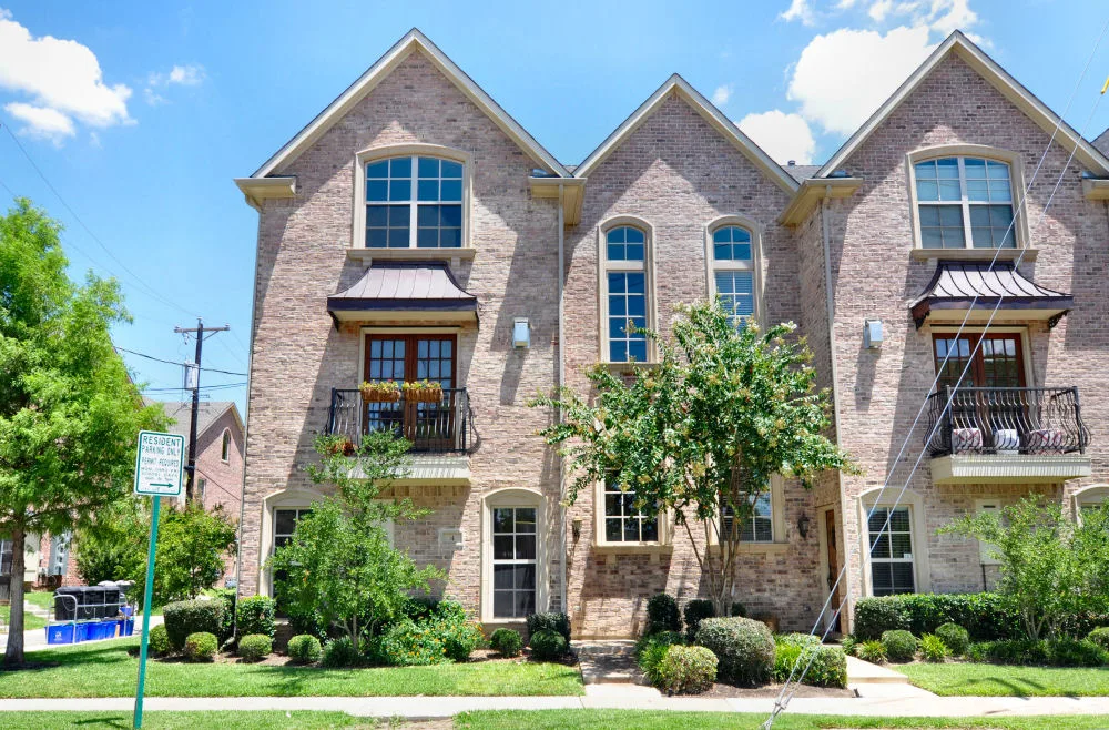 Brick townhome facade with steep gabled rooflines, iron balconies, and manicured landscaping