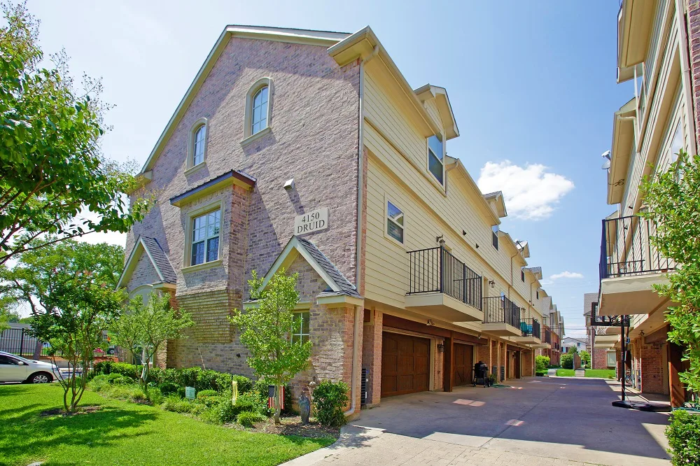Side view of the townhomes with a 4150 Druid address plaque, attached garages, and driveway