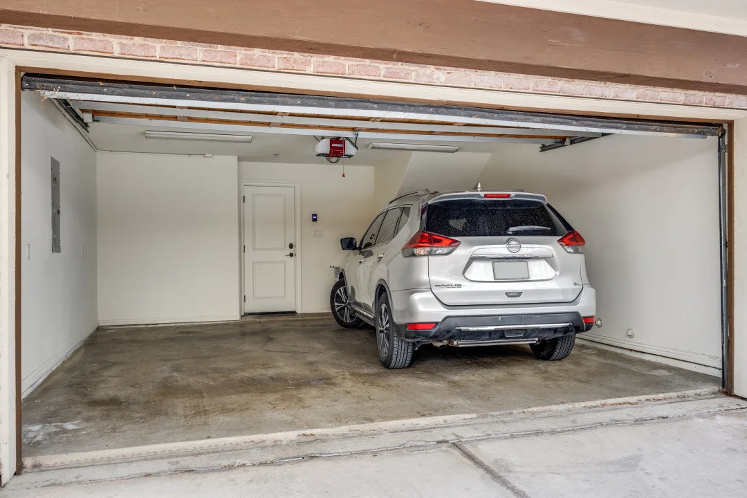 Private attached two-car garage with interior entry door and a resident SUV parked inside