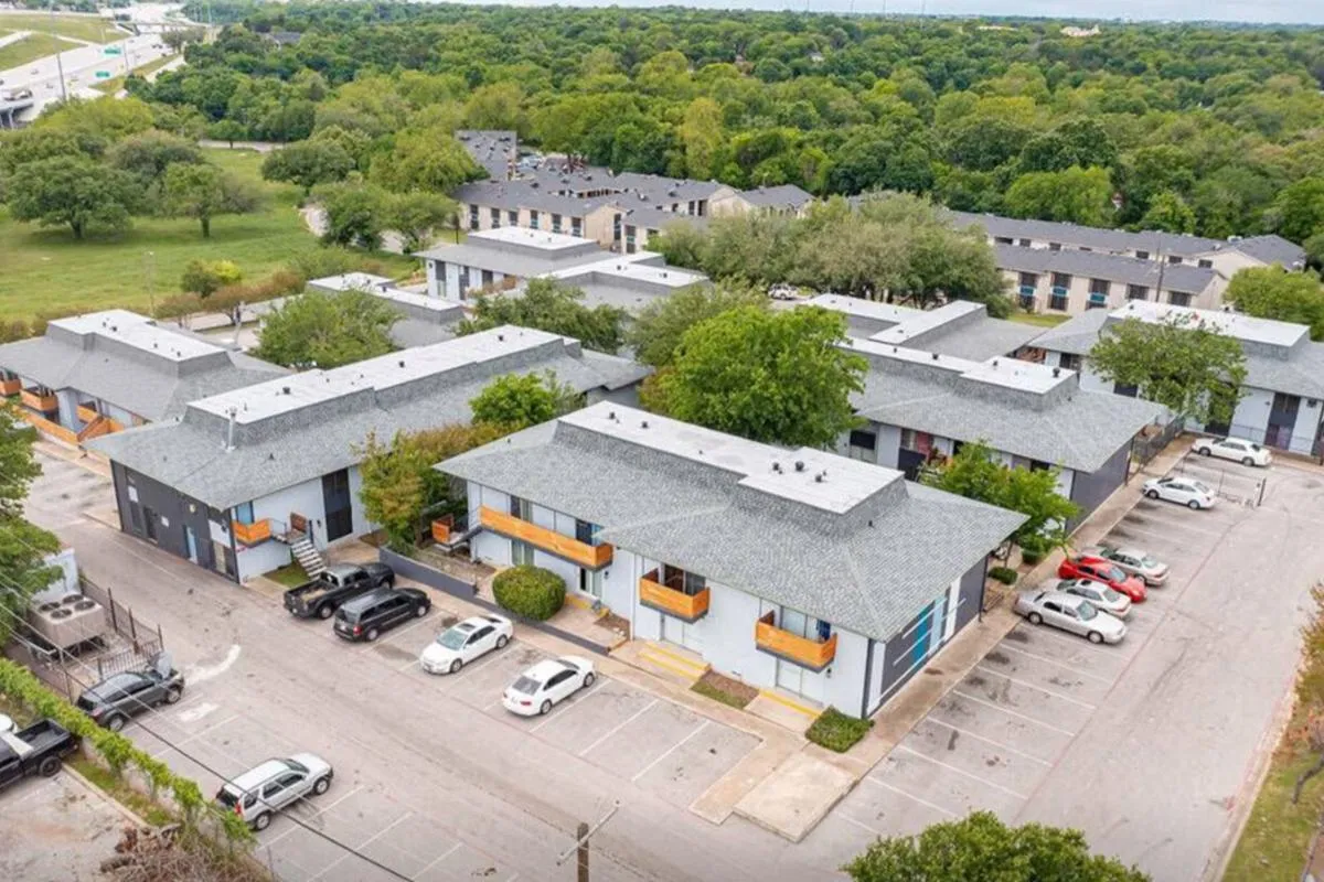 Aerial view of two-story buildings, parking lot, and tree-lined grounds at La Madera in Dallas