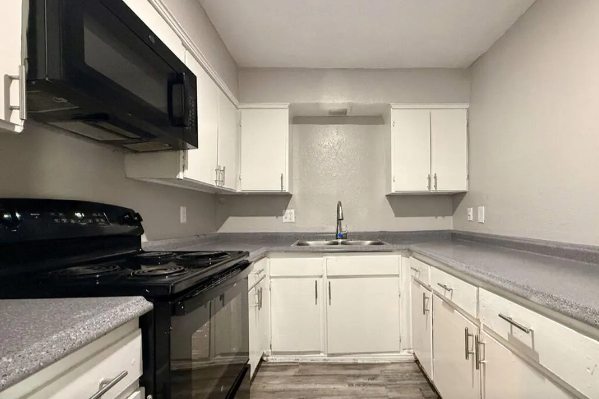 Kitchen with black appliances, white cabinets, and gray countertops at La Madera in Dallas