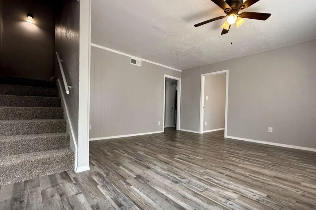 Living area with wood-style flooring, ceiling fan, and carpeted staircase at La Madera in Dallas