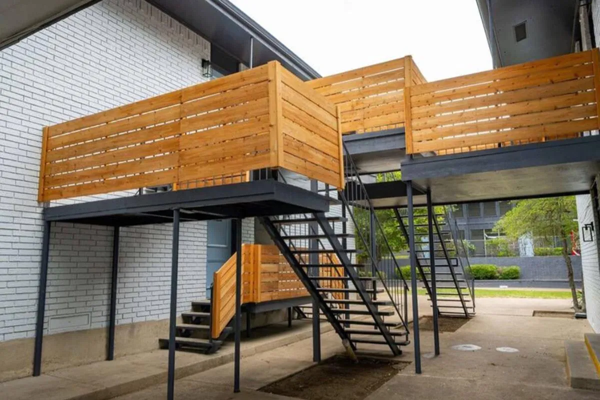 Metal exterior staircases with wood-slat privacy screens on second-floor walkways at La Madera in Dallas