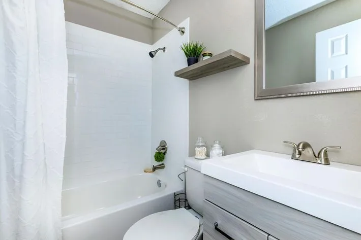 Updated bathroom with a white subway-tile tub surround, a vessel-style sink vanity, and a framed mirror