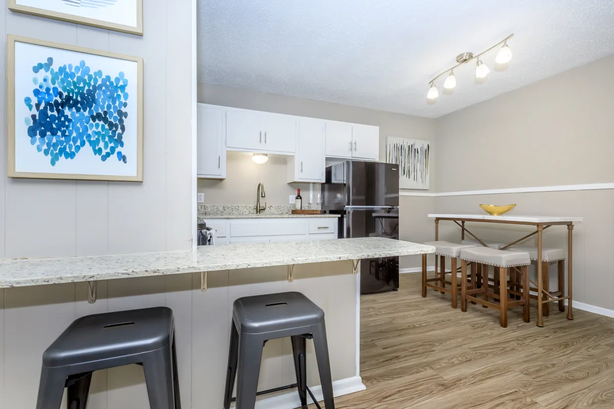 Dining nook with a marble-top bistro table and stools beside a breakfast bar and blue framed artwork