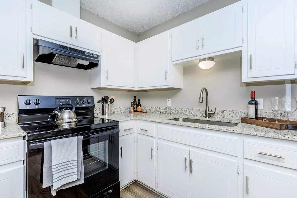 Renovated kitchen with white shaker cabinets, granite-style counters, a black range, and a stainless gooseneck faucet