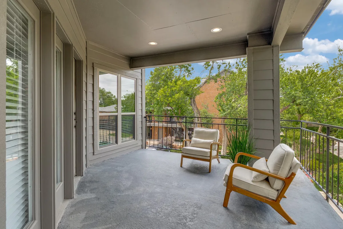 Private covered balcony with mid-century chairs and treetop views