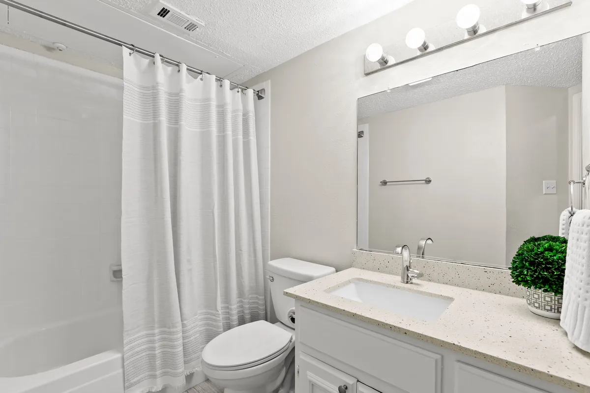 Bathroom with tub-shower combo, quartz vanity, and Hollywood-style vanity lighting