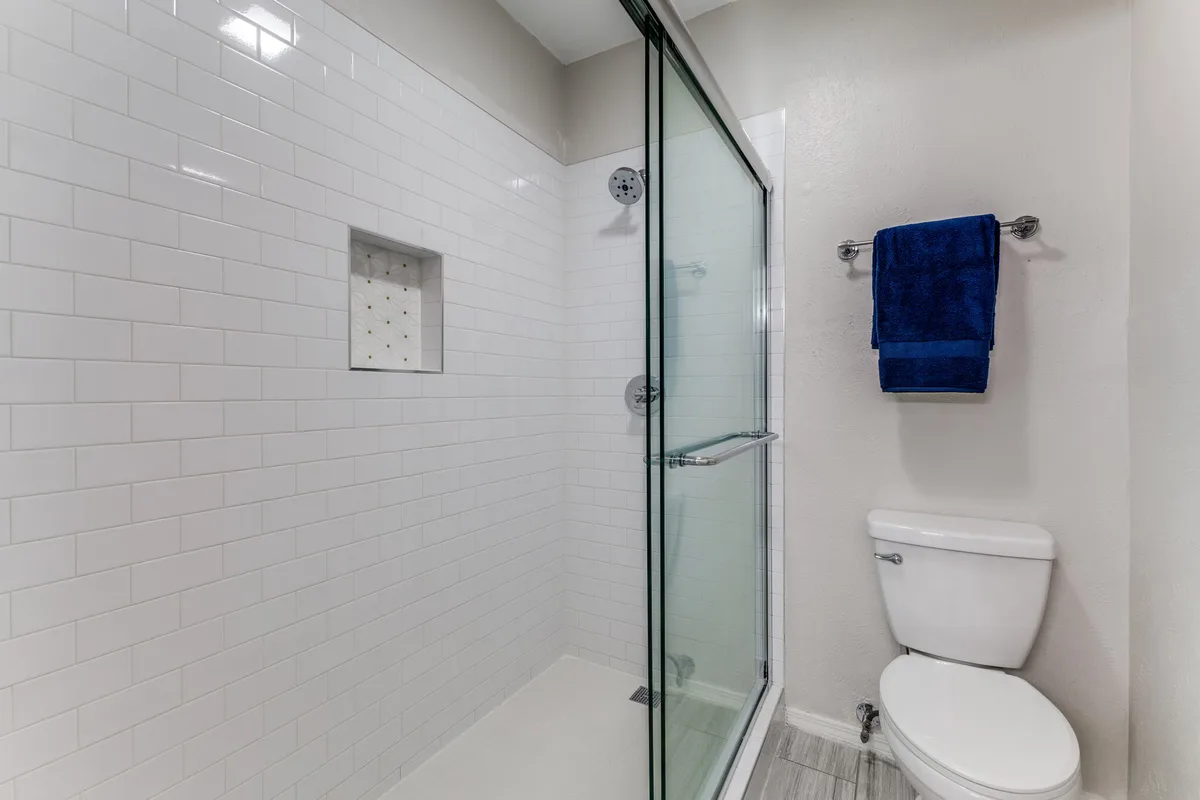 Bathroom with walk-in glass shower, white subway tile, and recessed shower niche