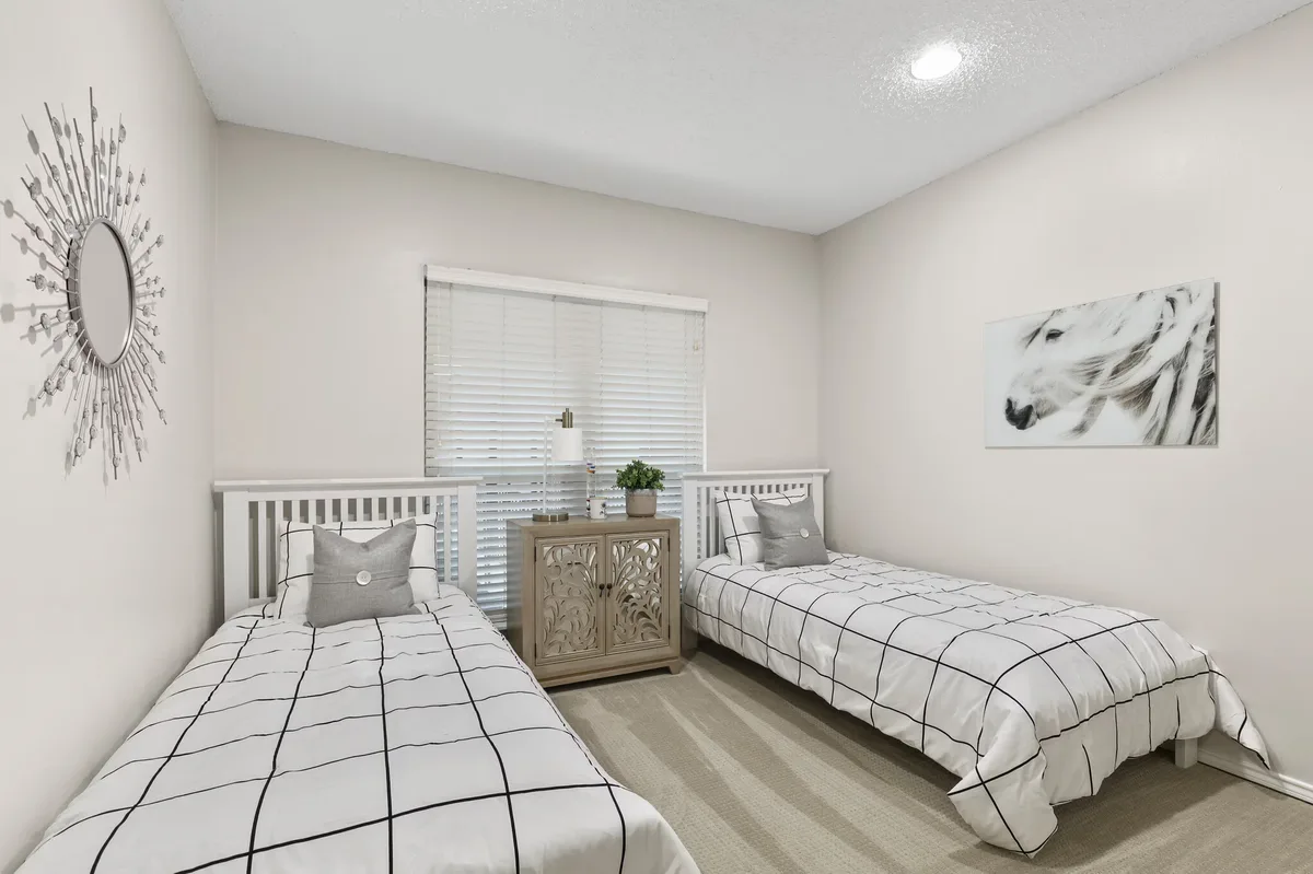 Secondary bedroom staged with two twin beds and carpeted floor