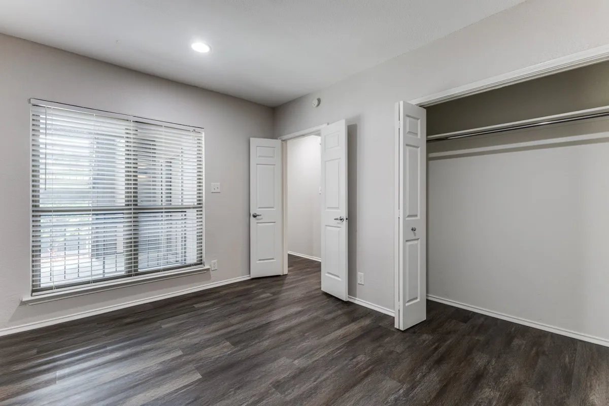 Bedroom with a double-door reach-in closet and wood-look flooring
