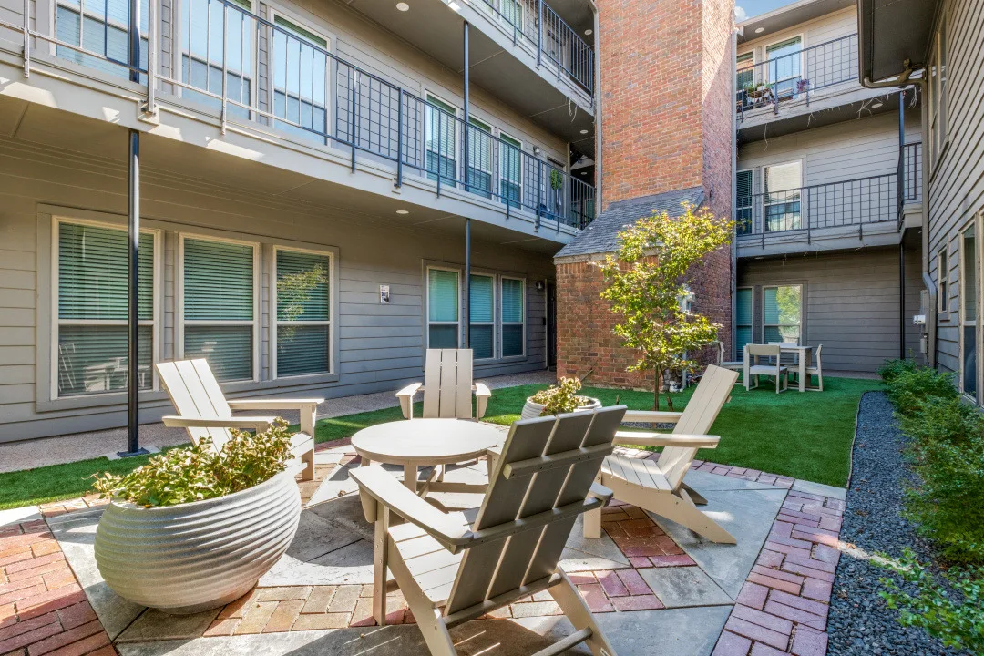 Landscaped courtyard with Adirondack chairs and a dining table on a brick paver patio