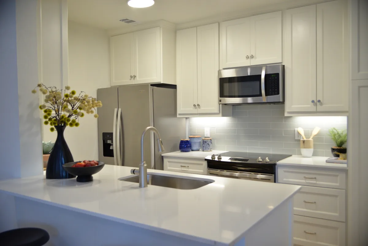 Kitchen with white shaker cabinets, stainless appliances, and a quartz peninsula with undermount sink
