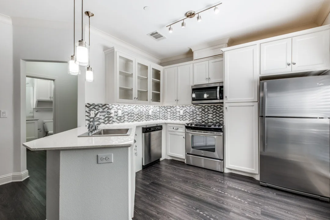 Kitchen with white cabinets, mosaic-tile backsplash, and stainless gas range and refrigerator