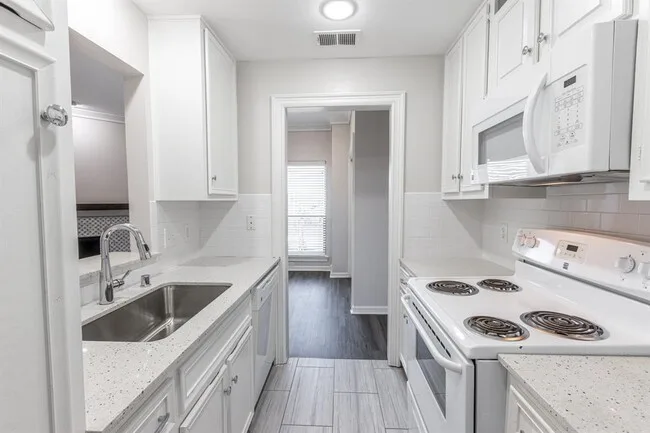 Galley kitchen with white cabinets, speckled counters, and a white electric range