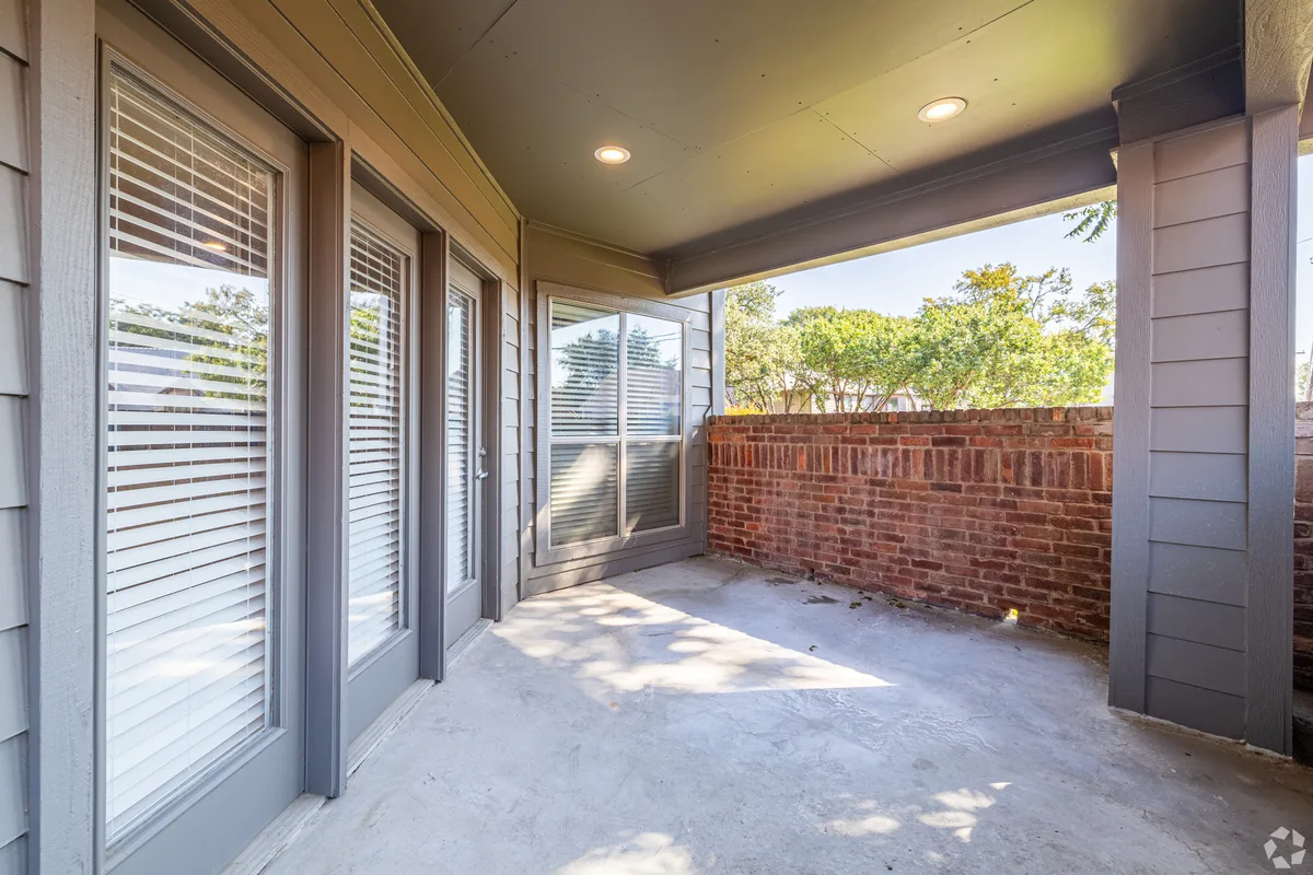 Private ground-floor patio with a brick half-wall and sliding glass doors