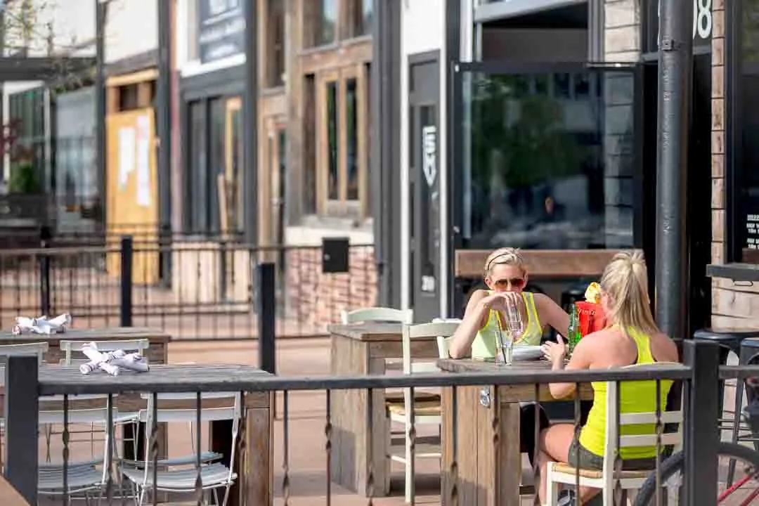 Friends at an outdoor patio table in front of a Bishop Arts restaurant