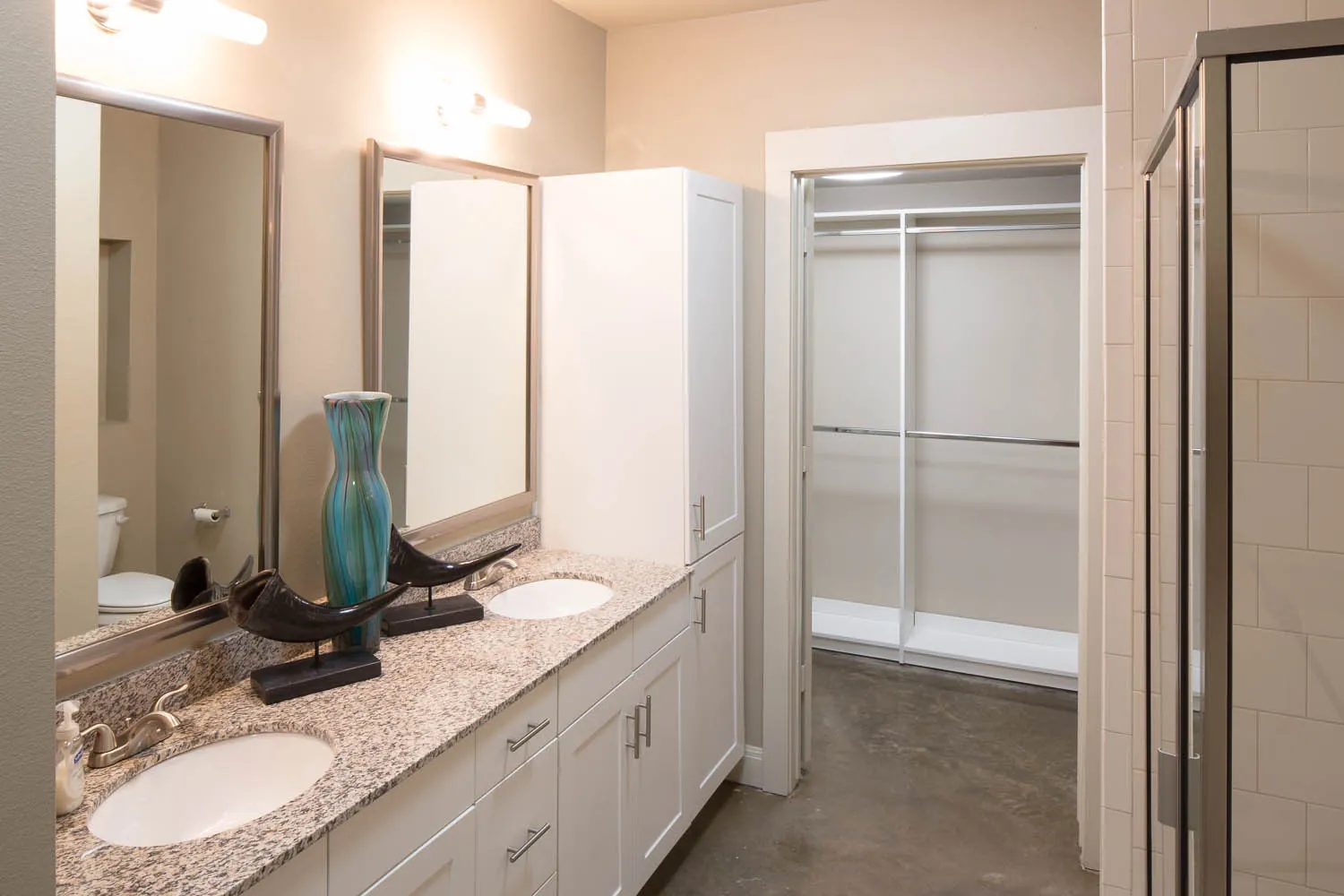 A double vanity with granite counters, opening to a walk-in closet