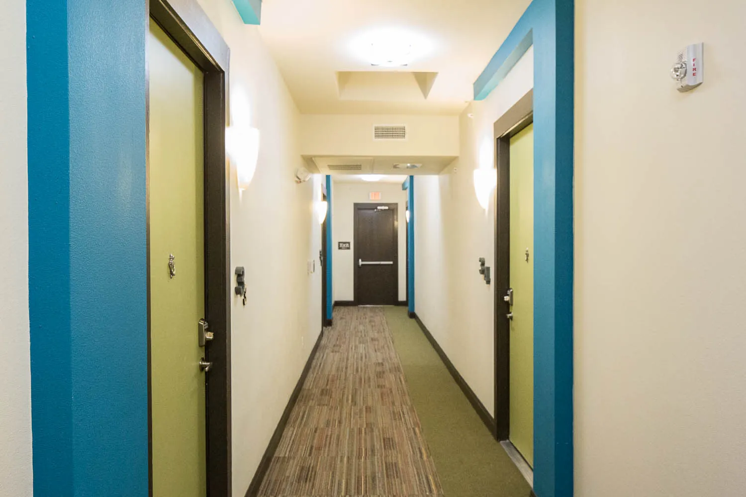 An interior corridor with pool blue door frames and wall sconces