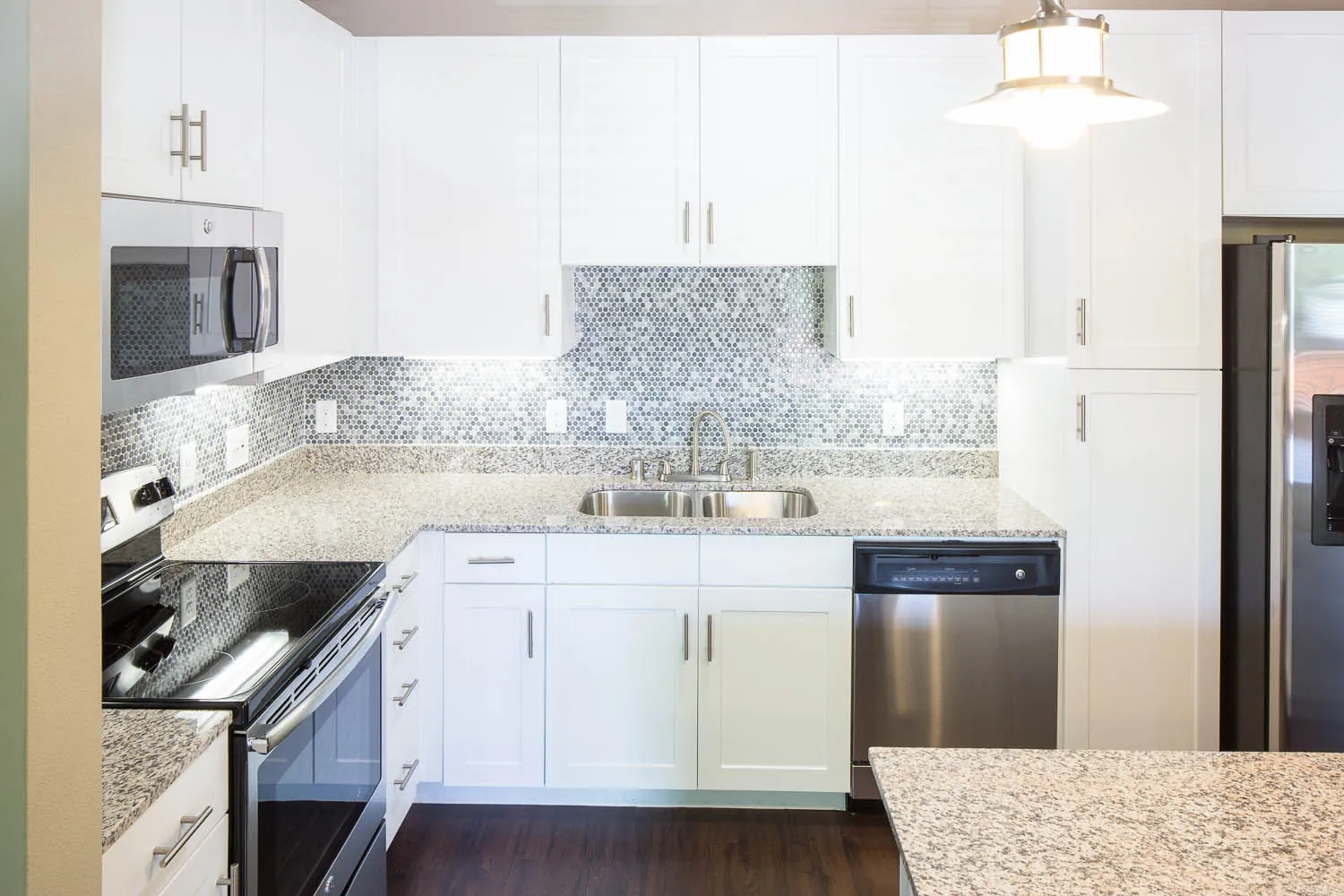 A kitchen with white cabinets, a mosaic tile backsplash and a stainless range