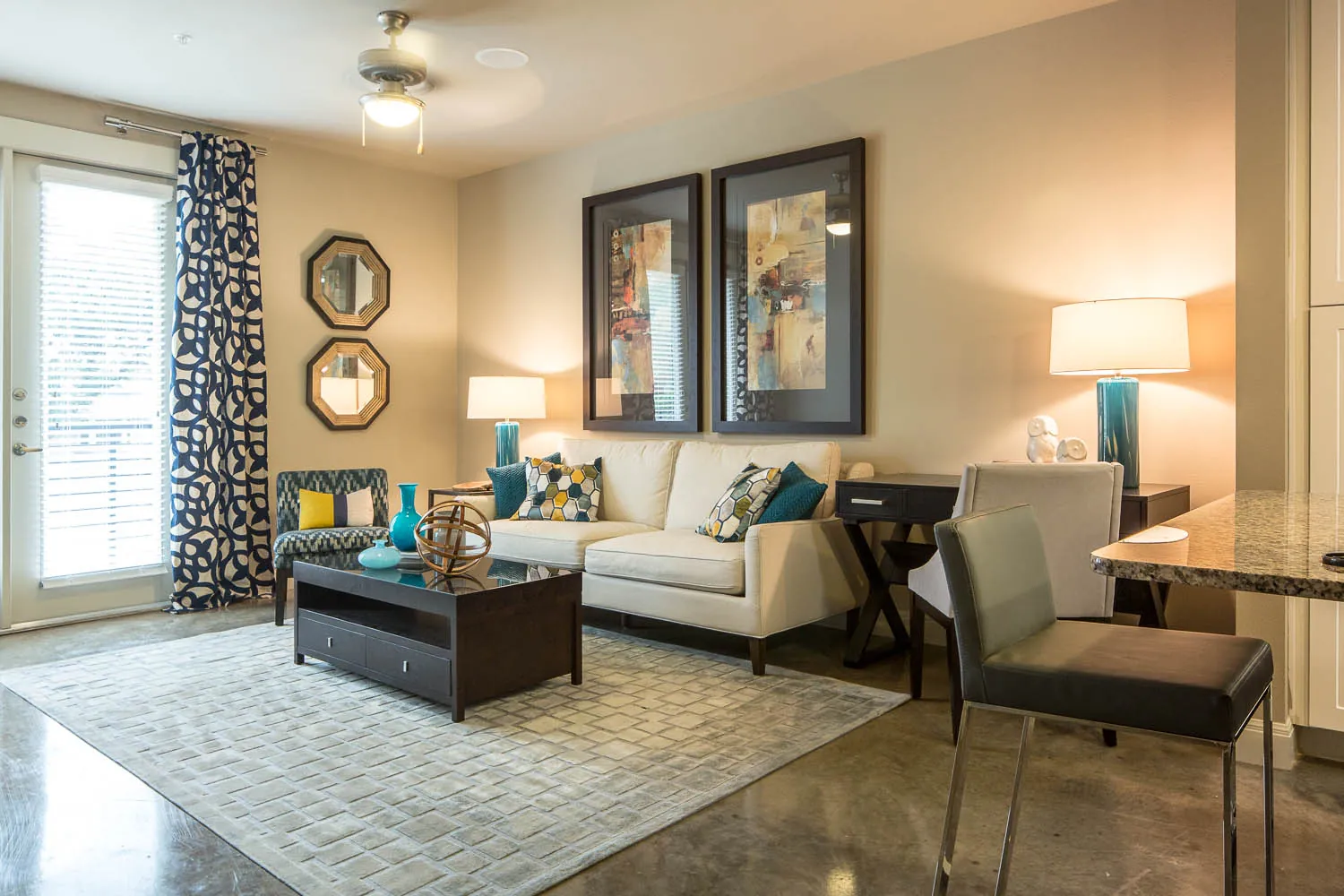 A staged living room with a sofa, a coffee table and a French door to the balcony