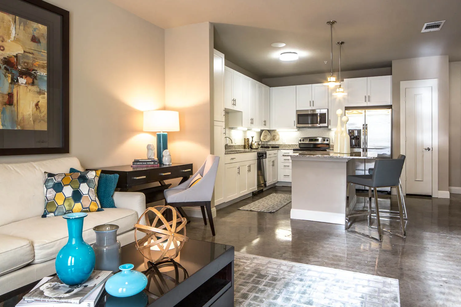 An open living room and kitchen with stained concrete floors and a granite island