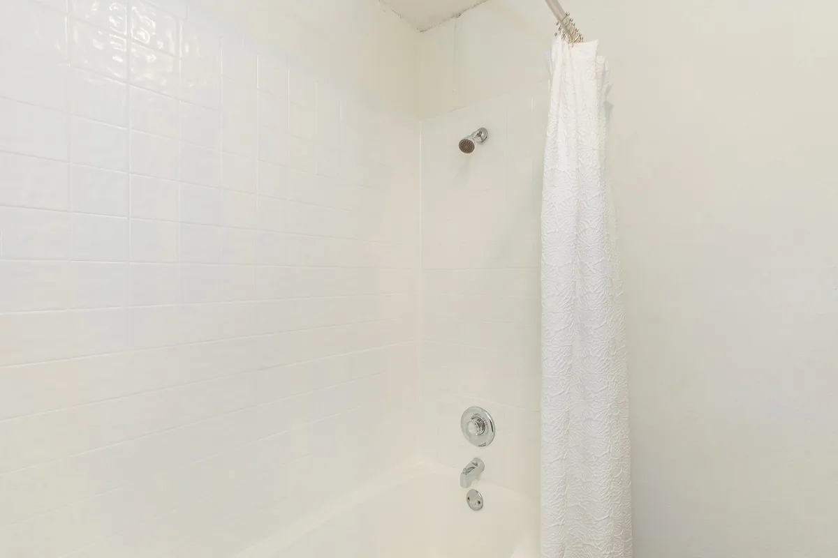 Tub and shower with a white subway-tile surround and fabric curtain
