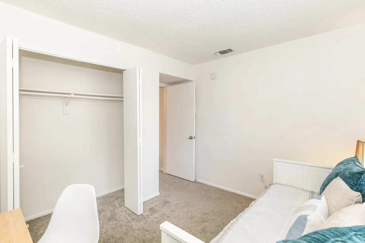 Carpeted bedroom with an open reach-in closet and hallway access
