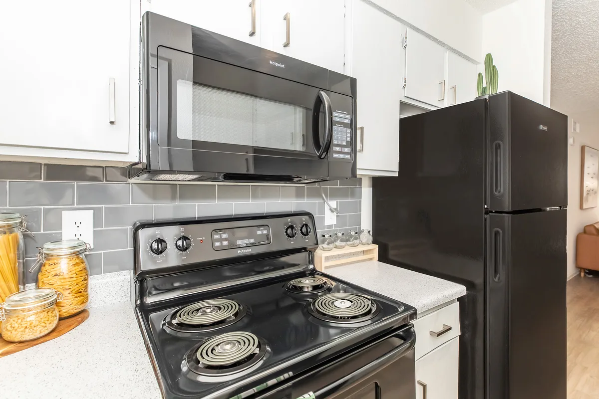 Kitchen with black appliances, white cabinetry, and a gray subway-tile backsplash