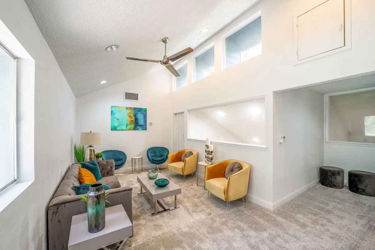 Bright living area with a vaulted ceiling, clerestory windows, and mid-century accent chairs