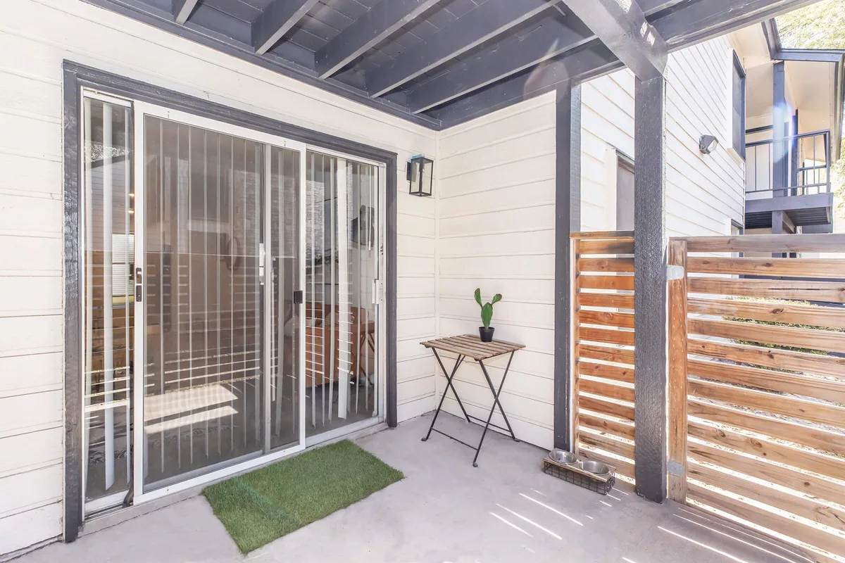 Private covered patio with a wood privacy screen and pet-friendly turf pad
