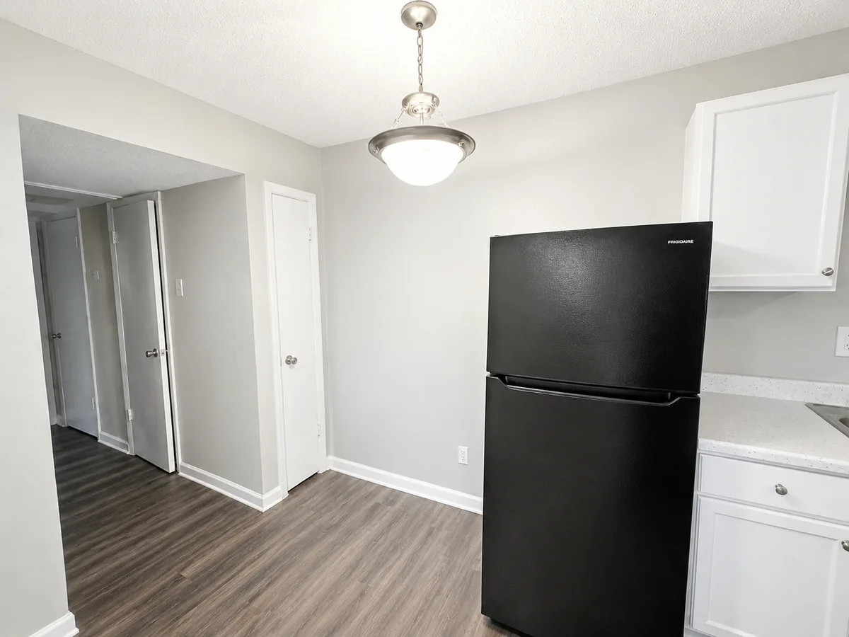 Dining area off the kitchen with pendant light, black refrigerator, and closet storage