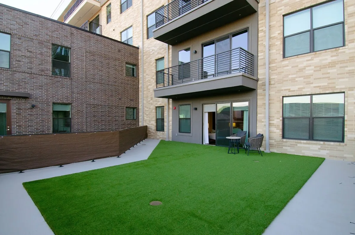 Ground-level courtyard with artificial-turf lawn, patio seating and tiered balconies above