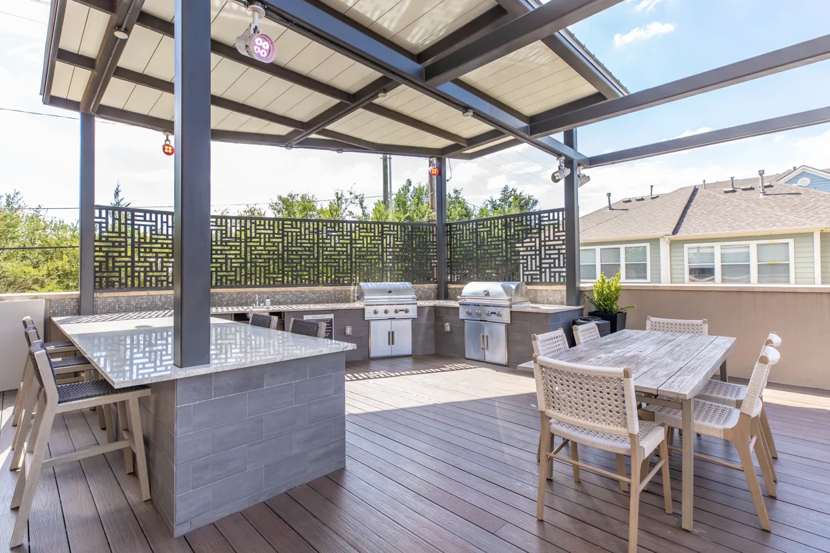 Covered rooftop outdoor kitchen with dual grills and a communal dining table