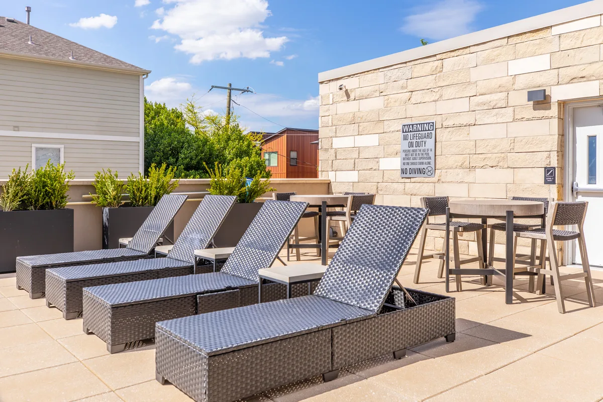 Rooftop sundeck with cushioned chaise loungers and bar-height cafe tables