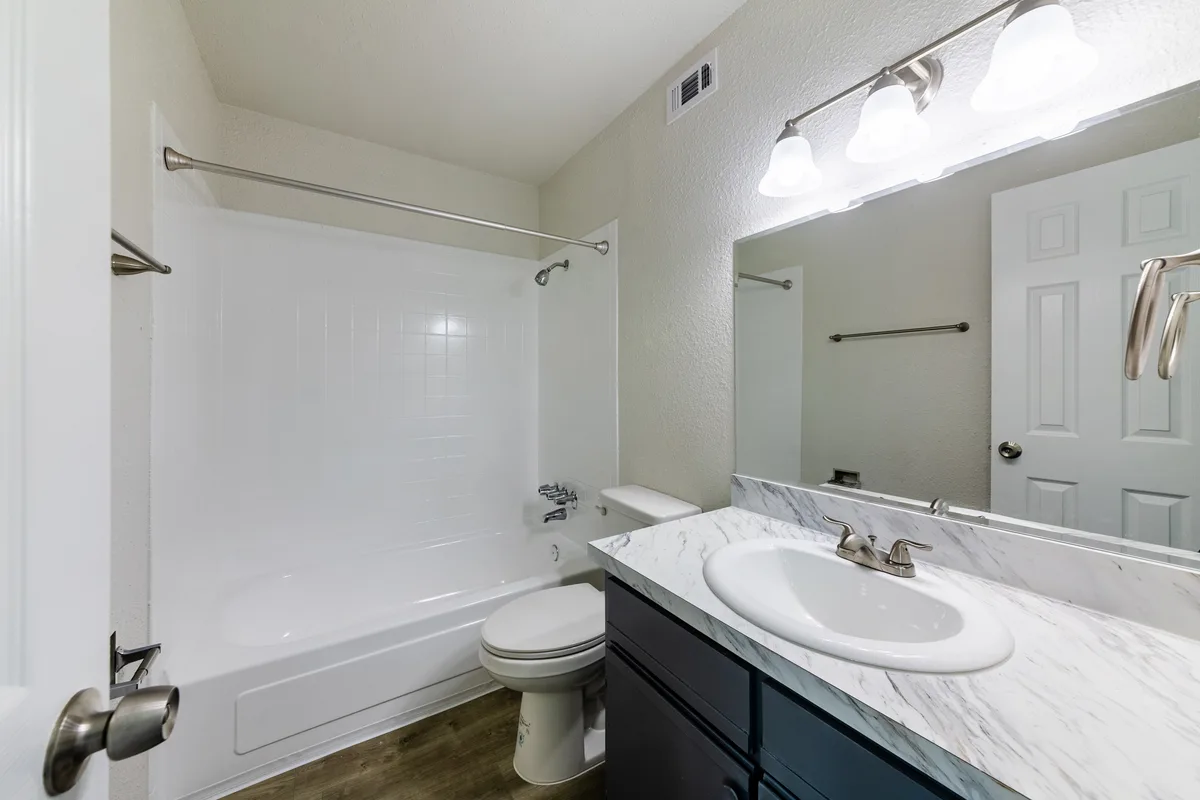 Bathroom with a tub-shower combination, marble-look vanity, and framed mirror