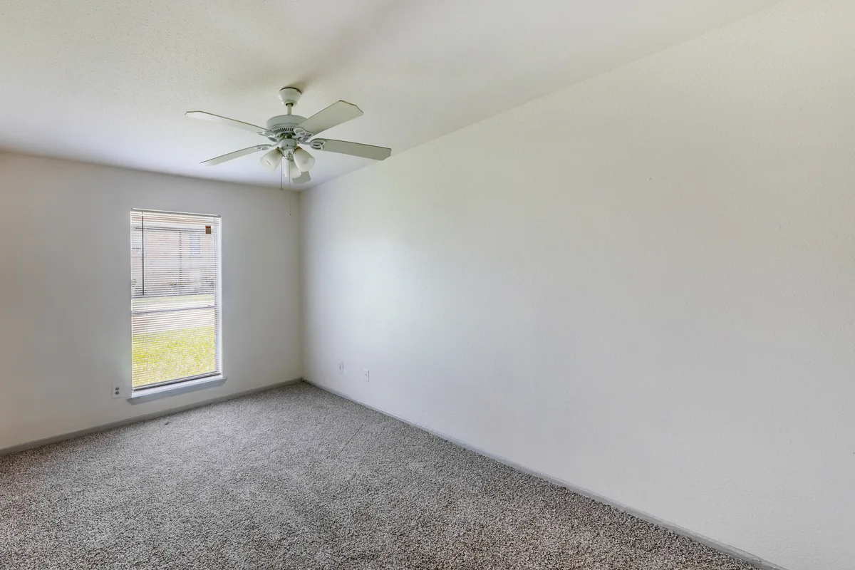 Carpeted bedroom with a ceiling fan and a blinds-covered window