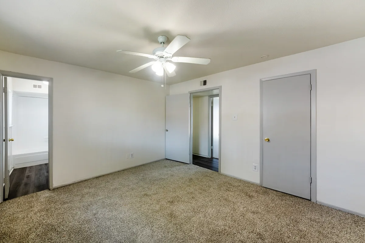 Carpeted bedroom with a ceiling fan, closet, and adjoining bathroom